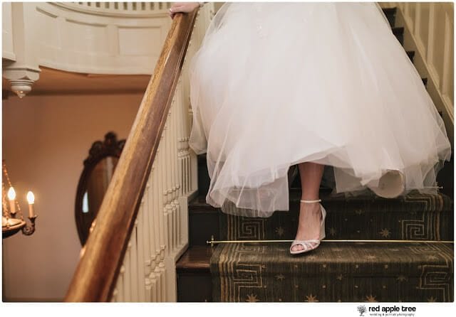 Bride walking down staircase in wedding dress